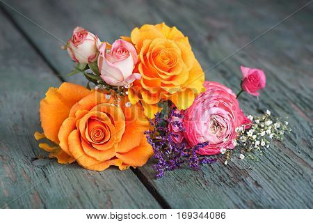 Colorful flower decoration with roses on an old rustic wooden table