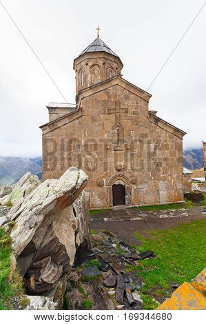 Gergeti Trinity Church Or Tsminda Sameba in the morning mist near village Stepantsminda, Georgia. Mount Kazbegi. Spring Or Summer Season.