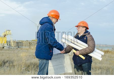 Engineers at a construction site with drawings in hand