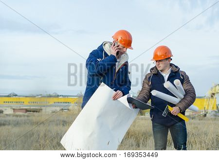 Engineers at a construction site with drawings in hand