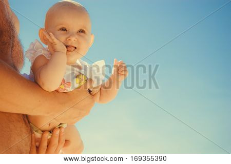 Closeup of happy sweet little baby in parent hands. Babyhood and parenting.
