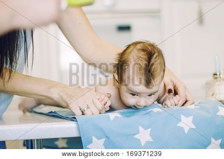 small child learns to help parents keep his head. baby lying on a blue diaper in a star. parental support.