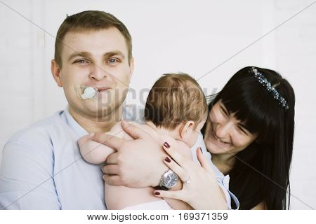 happy family consisting of mom and dad's baby boy. happy family relationships. mother entertains a child, his father holding him in her arms. his father in the mouth empty.