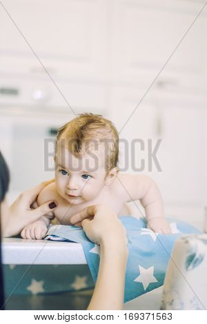 small child learns to help parents keep his head. baby lying on a blue diaper in a star. parental support.