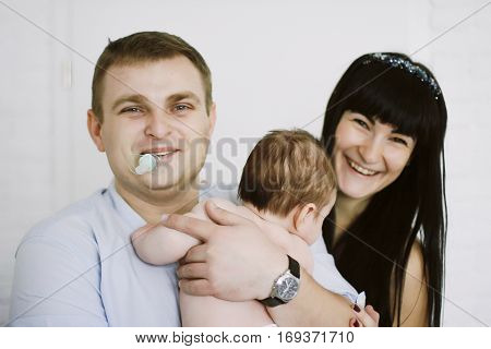 happy family consisting of mom and dad's baby boy. happy family relationships. mother entertains a child, his father holding him in her arms. his father in the mouth empty.