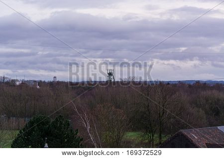 Image with lens flare effect and blur: Age headframe industrial monument in the Ruhr area before dawn sky with clouds.