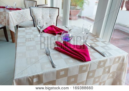 Empty glasses and dishes set in an empty interior new luxury restaurant with covered tables and crockery