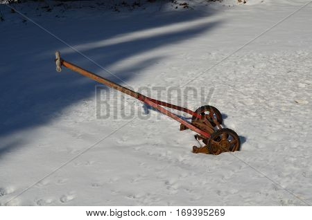 A antique reel type lawn mower in the snow