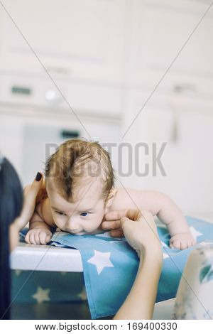 small child learns to help parents keep his head. baby lying on a blue diaper in a star. parental support.
