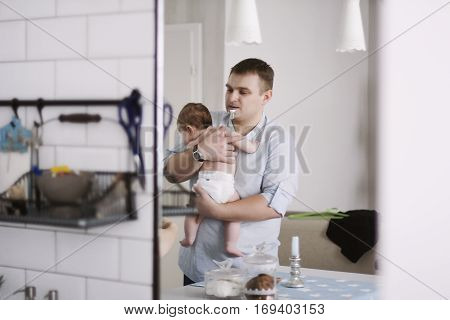 father with child in the kitchen with a pacifier in her mouth. family life
