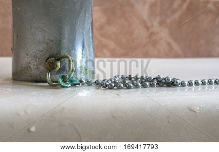 Calcium deposits on balls chain bathroom sink stopper brass oxide greenish color detail. Limescale problems