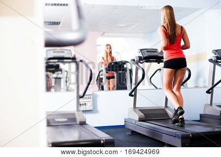 Active young woman running on treadmill at the gym exercising. Run on a machine.
