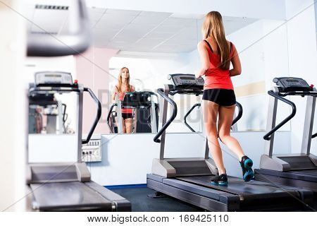 Active young woman running on treadmill at the gym exercising. Run on a machine.
