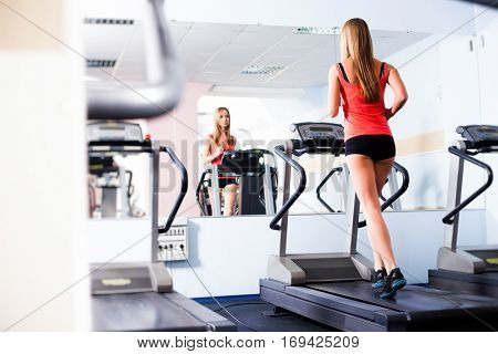 Active young woman running on treadmill at the gym exercising. Run on a machine.