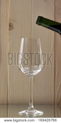 red wine being poured into a glass bottle of red wine with a brilliant glass on a wooden background on a glass stand