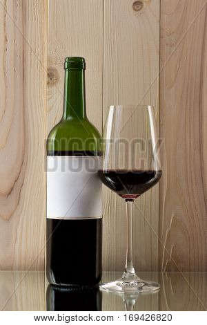 bottle of red wine with a brilliant glass on a wooden background on a glass stand