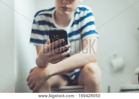 Teenager With A Smartphone On Toilet