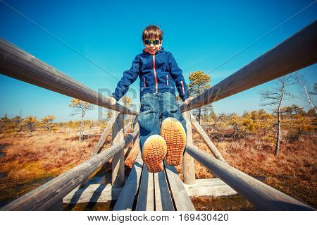 Cute little boy walking on trail in swamp and having fun, Kemeri national park, Latvia