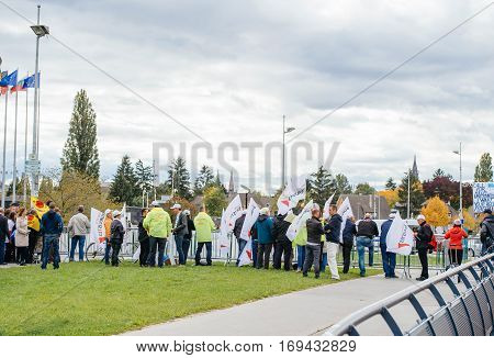 STRASBOURG FRANCE - OCT 7 2015: Rear view of tobacconists buralistes people protesting in front of the European Parliament building with flags placards while President Francois Hollande is entering the Parliament gates Confederation des buralistes