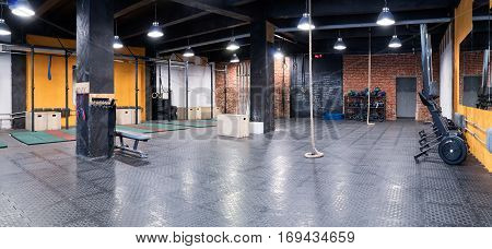Contemporary spacious cross-fit gym with trainers sport equipment and a rope for climbing