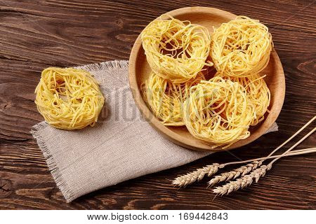 Raw pasta fettuccine in a wooden bowl on the table top view
