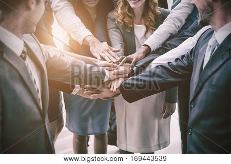 Well dressed business people with stacked hands in office