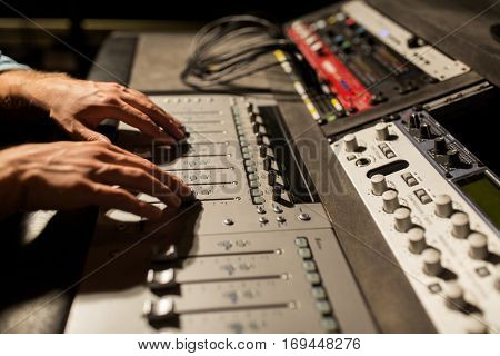 music, technology, people and equipment concept - man using mixing console in sound recording studio