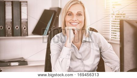 Smiling woman with chin on hand behind a desk inan office
