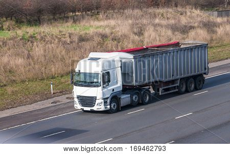 White lorry with tipping trailer in motion on the motorway