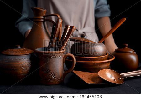 Brown dishware and woman on dark background