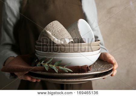 Female hands holding pile of dishware, closeup