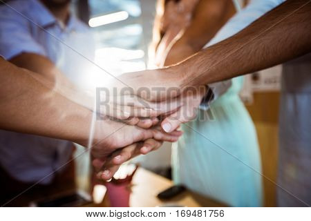 Casual colleagues putting hands together in the office