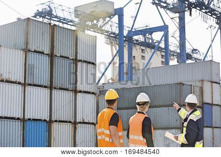 Rear view of workers inspecting cargo containers in shipping yard