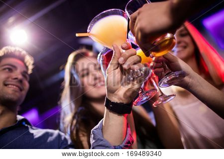 Smiling friends toasting cocktail at bar counter in bar