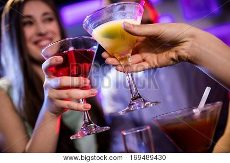 Friends toasting cocktail at bar counter in bar