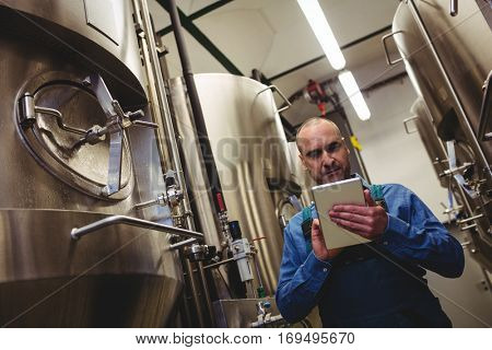 Low angle view of owner using tablet computer at brewery