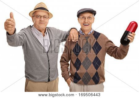 Senior making a thumb up sign with another senior holding a big pill isolated on white background