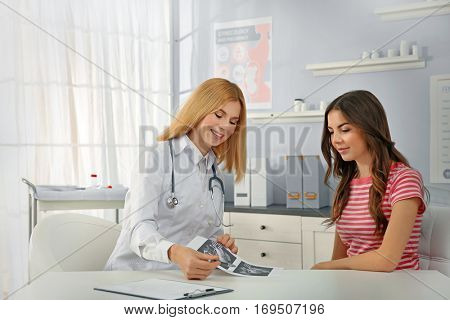 Doctor showing baby ultrasound image to pregnant woman