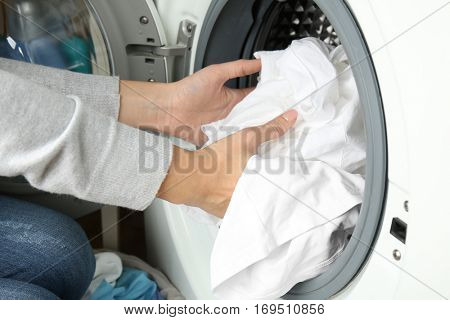 Female hands getting out clean clothes from washing machine