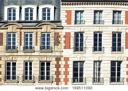 Typical Parisian architectural. The facade of a red brick building in Paris showing window details with wrought iron railings. 