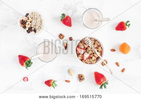 Healthy breakfast with muesli yogurt strawberry nuts on white background. Flat lay top view