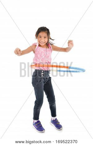 Portrait of happy little Asian child girl playing hulahoop on isolated white background