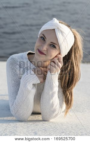 Young attractive woman wearing white knitted sweater and ear warmer turban. Lovely smile