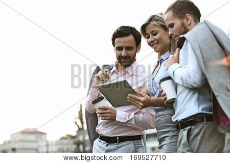 Low angle view of businesspeople using digital tablet against clear sky
