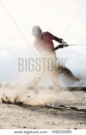 Middle-aged man splashing sand while playing at golf course