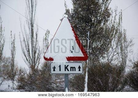 Road sign covered with snow in winter during the snawfall