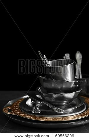 Silver dishware on table and black background