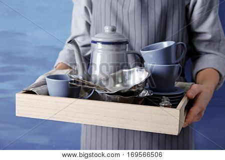 Closeup of female hands holding wooden tray with dishware