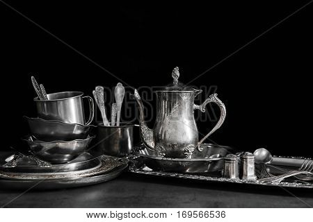 Silver dishware on table and black background
