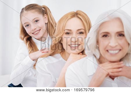 Have a great time. Delighted smiling family members smiling and resting together at home while resting on the couch